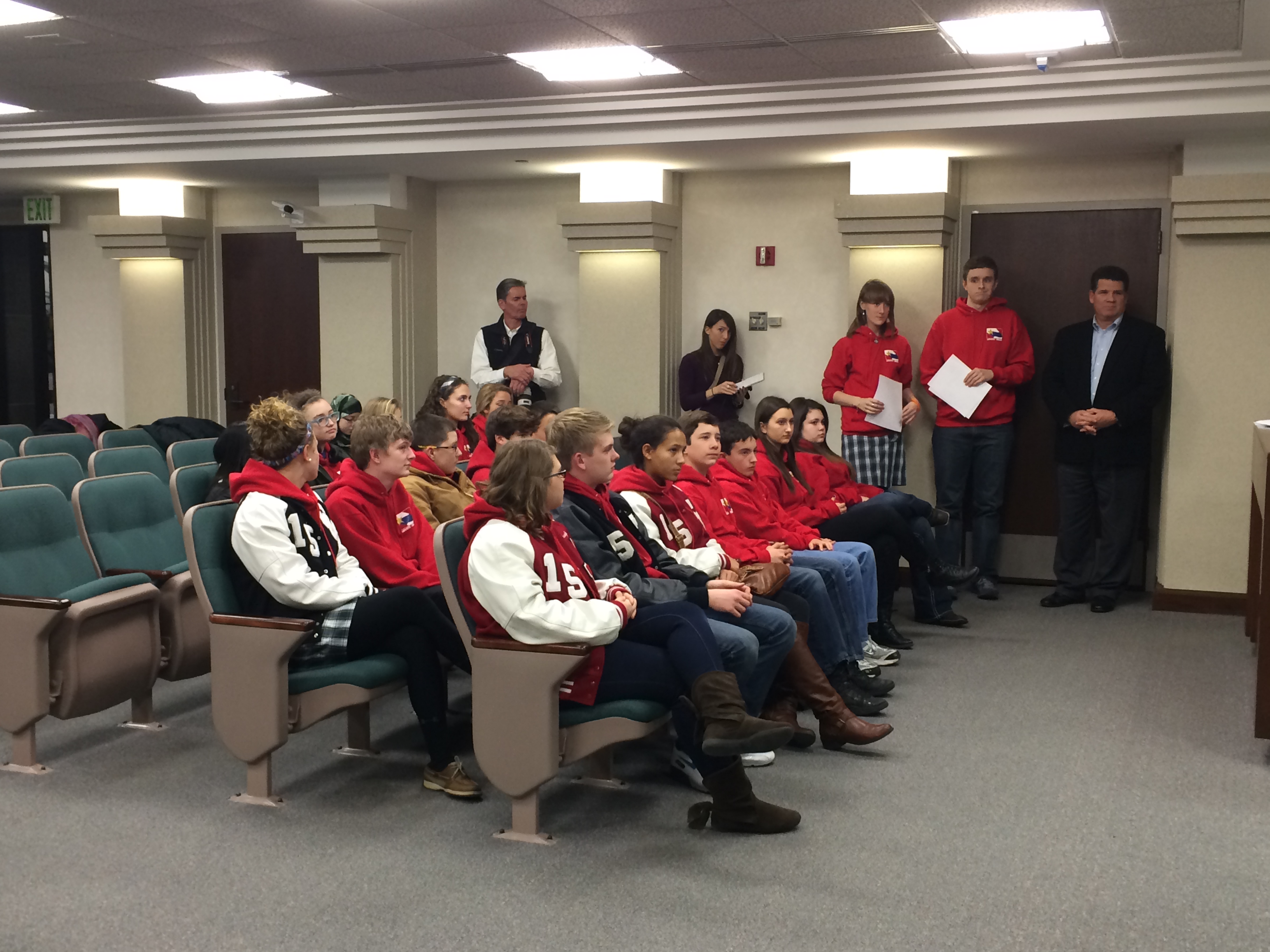 Teenagers sitting in seats listening to a speaker